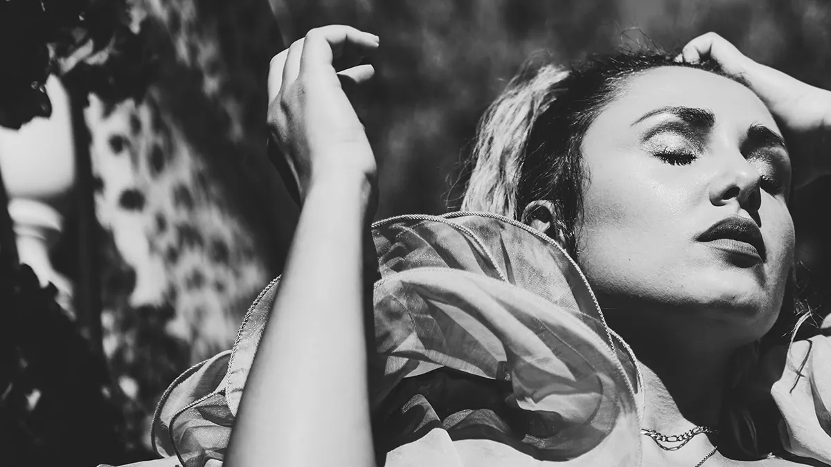A balck and white portrait of a woman touching her scalp
